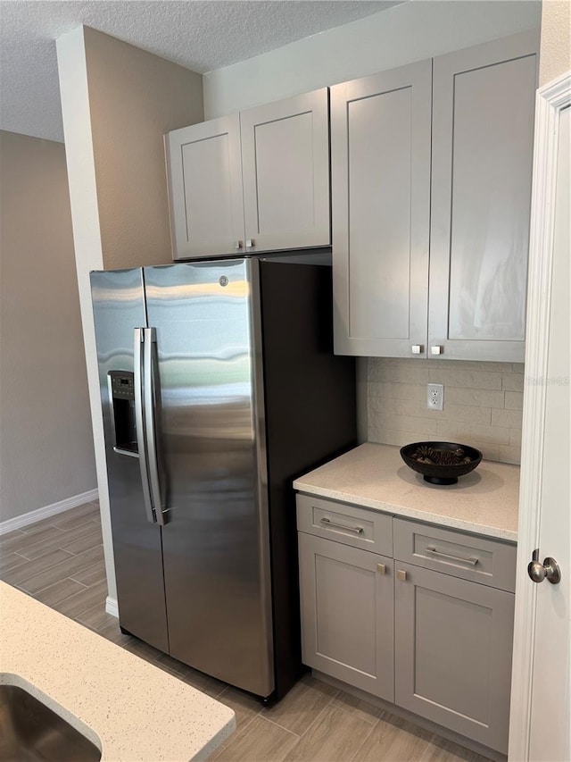 107 Grove St, Orlando, FL 32835 - kitchen featuring gray cabinetry, stainless steel fridge with ice dispenser, tasteful backsplash, light wood-type flooring, and light stone countertops