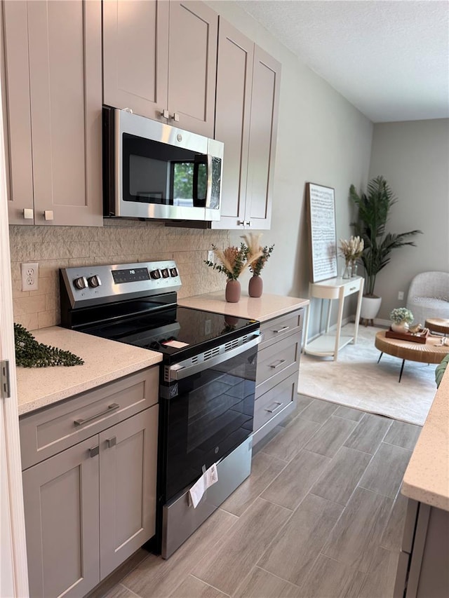 107 Grove St, Orlando, FL 32835 - kitchen featuring stainless steel appliances, gray cabinetry, and backsplash