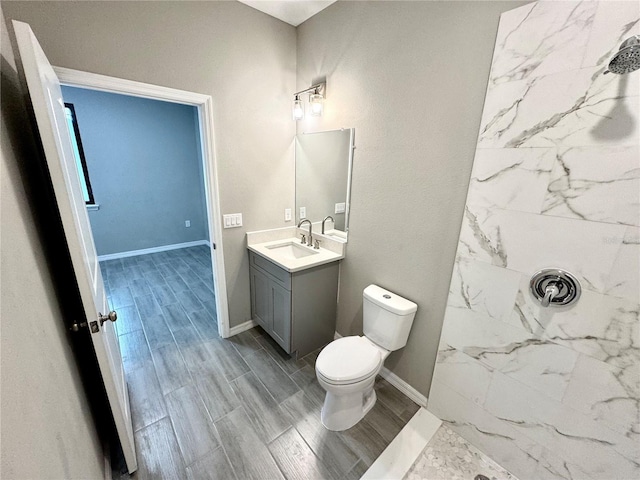 107 Grove St, Orlando, FL 32835 - bathroom featuring toilet, vanity, a marble finish shower, wood tiled floors, and baseboards