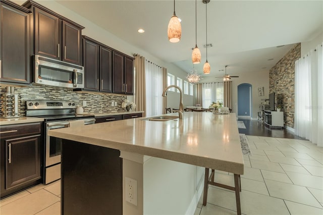 8268 Bellow St, Orlando, FL 32827 - kitchen featuring appliances with stainless steel finishes, a sink, light countertops, a center island with sink, and tasteful backsplash