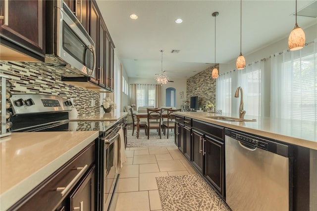 8268 Bellow St, Orlando, FL 32827 - kitchen with appliances with stainless steel finishes, a sink, light countertops, backsplash, and hanging light fixtures