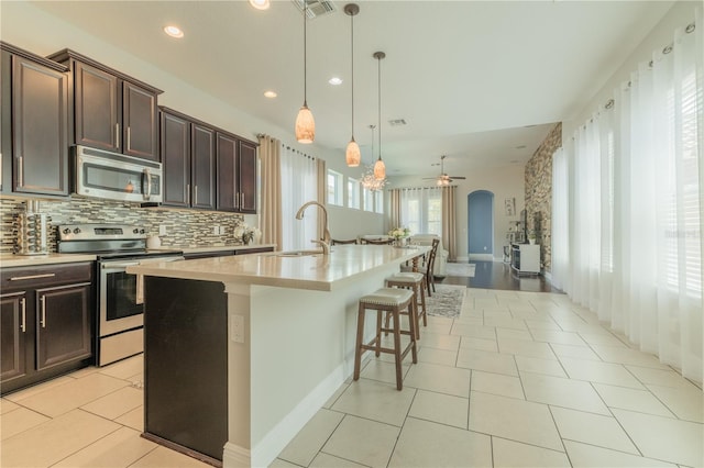 8268 Bellow St, Orlando, FL 32827 - kitchen featuring stainless steel appliances, a sink, light countertops, a center island with sink, and backsplash