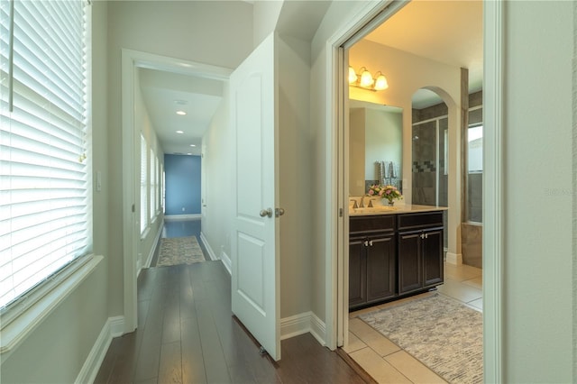 8268 Bellow St, Orlando, FL 32827 - hall with arched walkways, baseboards, light wood finished floors, and a sink