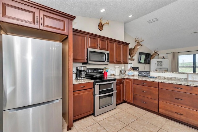 16386 SE 156th Place Rd, Weirsdale, FL 32195 - kitchen with stainless steel appliances, a textured ceiling, lofted ceiling, light stone counters, and light tile patterned flooring