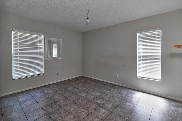 15372 George Blvd, Clearwater, FL 33760 - unfurnished room with plenty of natural light, a textured ceiling, tile patterned flooring, and baseboards