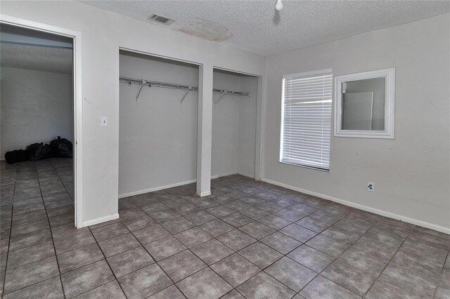 15372 George Blvd, Clearwater, FL 33760 - unfurnished bedroom with two closets, a textured ceiling, and tile patterned flooring