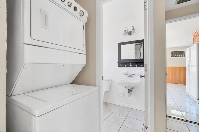 6940 82nd Ave N, Pinellas Park, FL 33781 - laundry area featuring stacked washer / drying machine, light tile patterned floors, and baseboards