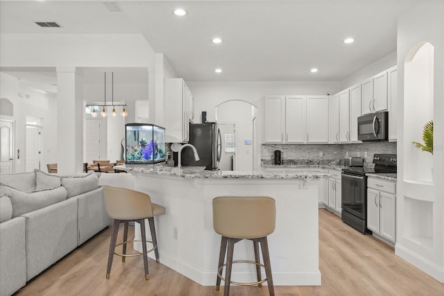 356 Via Tuscany Loop, Lake Mary, FL 32746 - kitchen with black appliances, a kitchen bar, open floor plan, a peninsula, and backsplash