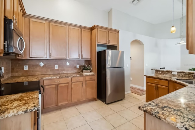 2481 Deer Creek Blvd, Saint Cloud, FL 34772 - kitchen with stainless steel appliances, arched walkways, light stone counters, tasteful backsplash, and light tile patterned floors