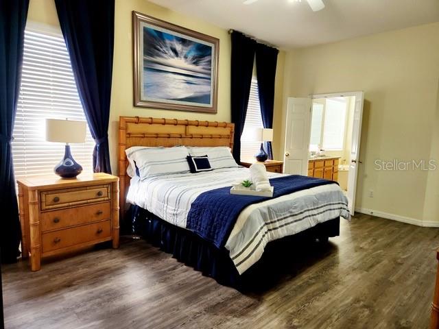 236 Boxwood Dr, Davenport, FL 33837 - bedroom with dark wood-type flooring, ensuite bath, a ceiling fan, and baseboards
