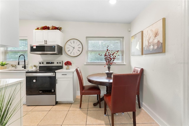 5115 W Livingston St, Orlando, FL 32811 - kitchen featuring appliances with stainless steel finishes, light countertops, white cabinets, and light tile patterned flooring