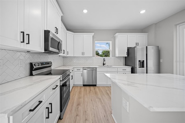 3944 SW 130th Loop, Ocala, FL 34473 - kitchen featuring appliances with stainless steel finishes, a sink, white cabinetry, light wood-style floors, and decorative backsplash