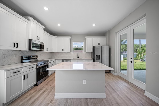 3944 SW 130th Loop, Ocala, FL 34473 - kitchen featuring stainless steel appliances, a sink, a kitchen island, tasteful backsplash, and light wood finished floors