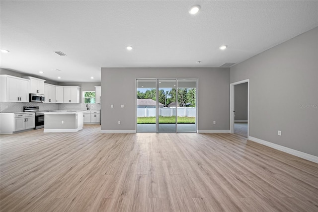 3944 SW 130th Loop, Ocala, FL 34473 - unfurnished living room featuring healthy amount of natural light, baseboards, recessed lighting, and light wood-style floors