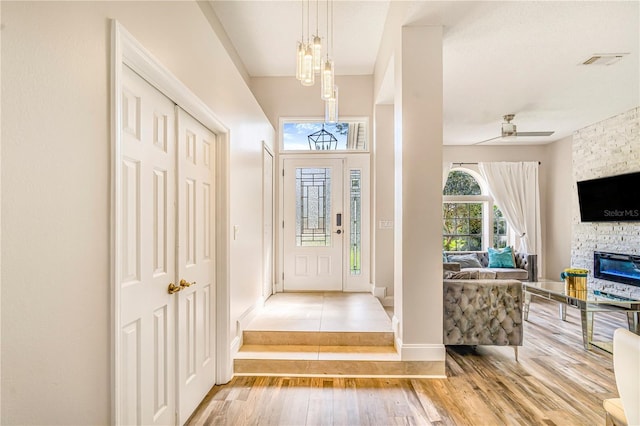 7838 Rollingridge Ct, Orlando, FL 32835 - entrance foyer with wood finished floors, a stone fireplace, a ceiling fan, and baseboards