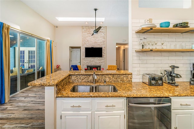7838 Rollingridge Ct, Orlando, FL 32835 - kitchen with stainless steel dishwasher, a sink, tasteful backsplash, open shelves, and light stone counters