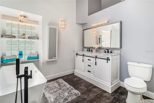 7838 Rollingridge Ct, Orlando, FL 32835 - bathroom featuring baseboards, toilet, a freestanding bath, and double vanity