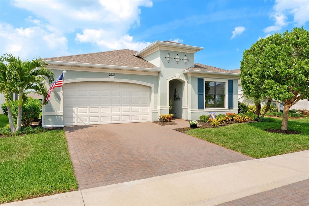 2272 Great Belt Cir, Melbourne, FL 32940 - mediterranean / spanish house with decorative driveway, a front lawn, a garage, stucco siding, and roof with shingles