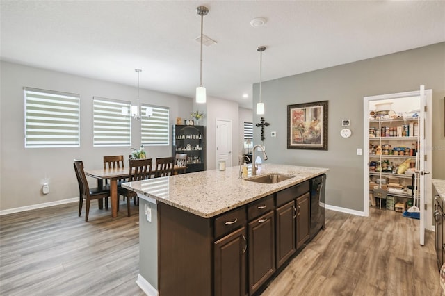 2941 Marlberry Ln, Clermont, FL 34714 - kitchen featuring light wood-style floors, dark brown cabinetry, a kitchen island with sink, dishwasher, and pendant lighting