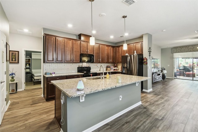 2941 Marlberry Ln, Clermont, FL 34714 - kitchen featuring black appliances, backsplash, dark wood-style flooring, light stone counters, and an island with sink