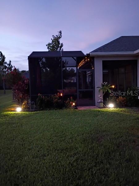 2941 Marlberry Ln, Clermont, FL 34714 - yard at dusk with a sunroom and a lawn