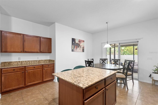 30245 Cheval St, Mount Dora, FL 32757 - kitchen with pendant lighting, brown cabinetry, a kitchen island, light stone countertops, and baseboards