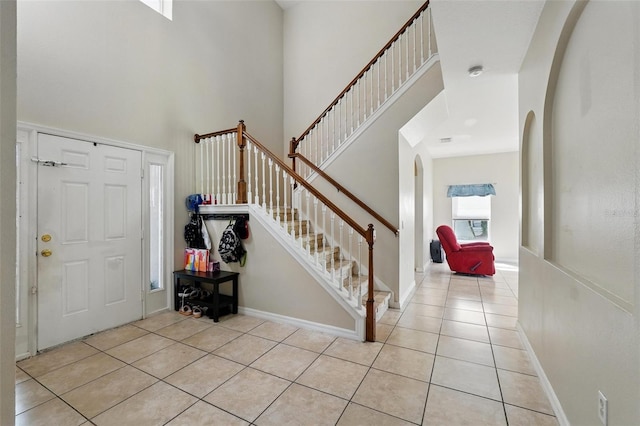 4208 Lugano Ct, Kissimmee, FL 34746 - foyer with arched walkways, light tile patterned floors, a towering ceiling, stairway, and baseboards