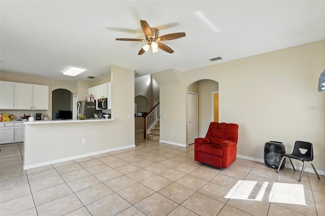 4208 Lugano Ct, Kissimmee, FL 34746 - sitting room with arched walkways, a ceiling fan, stairway, and light tile patterned floors