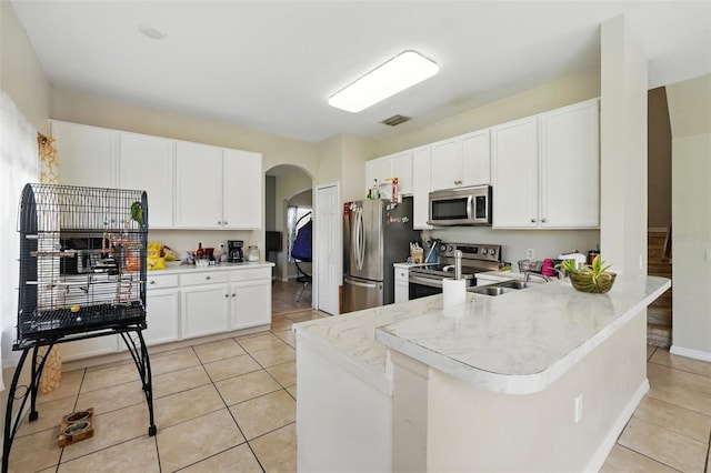 4208 Lugano Ct, Kissimmee, FL 34746 - kitchen featuring stainless steel appliances, arched walkways, a sink, light tile patterned floors, and white cabinets