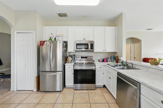 4208 Lugano Ct, Kissimmee, FL 34746 - kitchen featuring appliances with stainless steel finishes, a sink, arched walkways, and white cabinets
