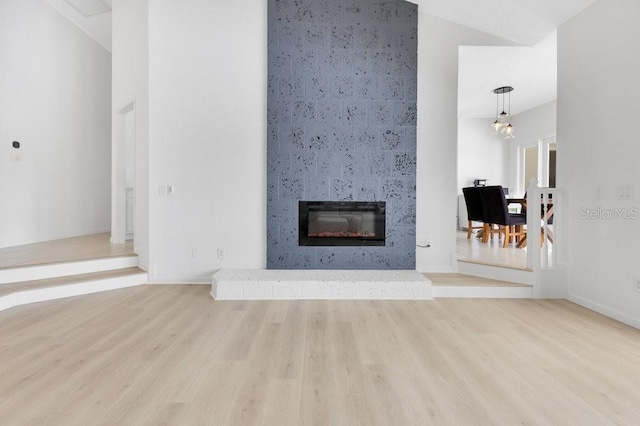 5913 Masters Blvd, Orlando, FL 32819 - unfurnished living room featuring a large fireplace, wood finished floors, a towering ceiling, and baseboards