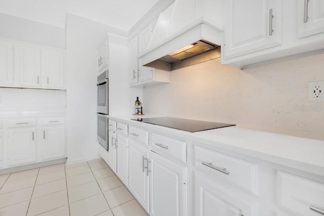 5913 Masters Blvd, Orlando, FL 32819 - kitchen featuring black electric stovetop, premium range hood, white cabinets, light tile patterned floors, and light countertops