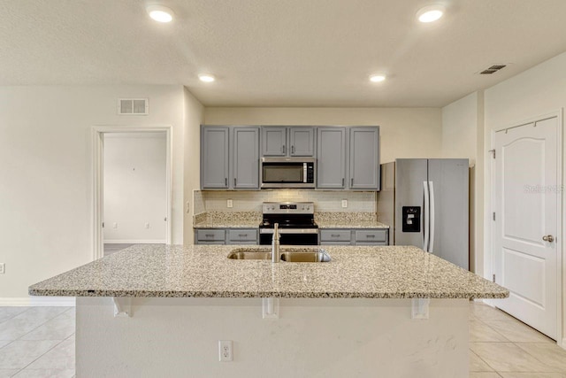 868 Brooklet Dr, Davenport, FL 33837 - kitchen with appliances with stainless steel finishes, gray cabinetry, a sink, light tile patterned floors, and a breakfast bar area