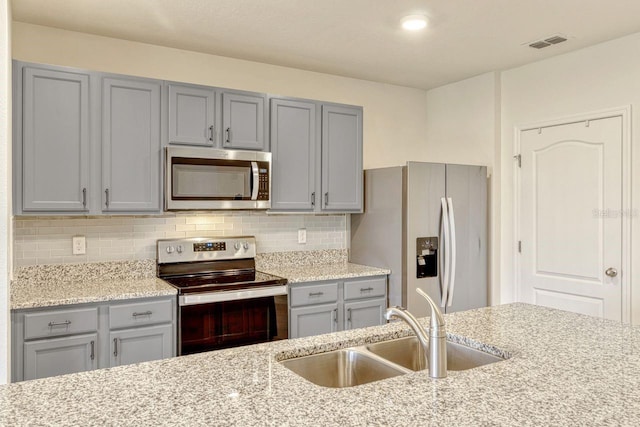 868 Brooklet Dr, Davenport, FL 33837 - kitchen featuring stainless steel appliances, gray cabinets, a sink, decorative backsplash, and light stone countertops