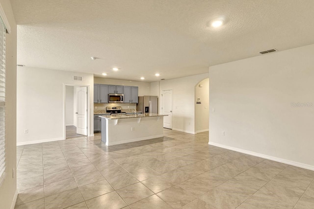 868 Brooklet Dr, Davenport, FL 33837 - kitchen featuring gray cabinets, stainless steel appliances, a textured ceiling, arched walkways, and open floor plan