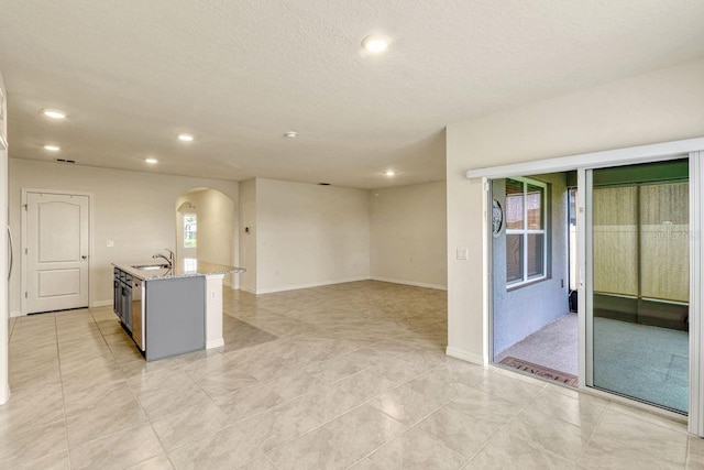 868 Brooklet Dr, Davenport, FL 33837 - kitchen with arched walkways, recessed lighting, a sink, light tile patterned flooring, and light stone countertops