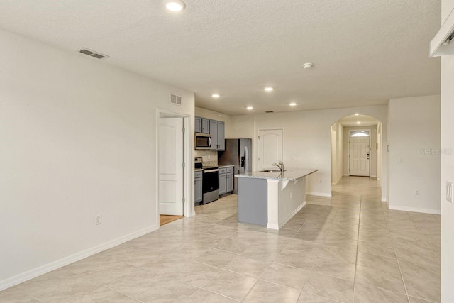 868 Brooklet Dr, Davenport, FL 33837 - kitchen with appliances with stainless steel finishes, arched walkways, a breakfast bar area, a center island with sink, and recessed lighting