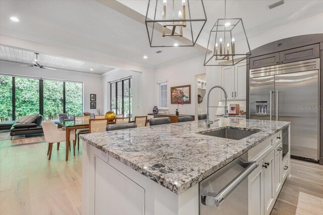 521 S Phelps Ave, Winter Park, FL 32789 - kitchen featuring appliances with stainless steel finishes, a sink, open floor plan, light wood-type flooring, and an island with sink