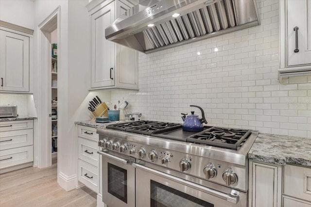 521 S Phelps Ave, Winter Park, FL 32789 - kitchen with double oven range, premium range hood, backsplash, light stone countertops, and light wood finished floors
