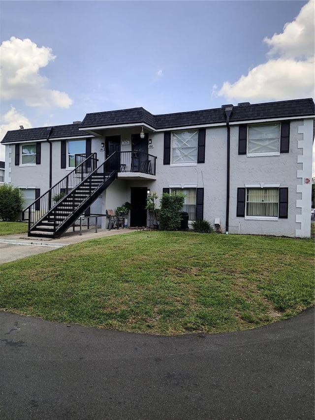 7676 Forest City Rd 150 A/K/A Unit B, Orlando, FL 32810 - view of front facade with stairway, a front lawn, stucco siding, and mansard roof
