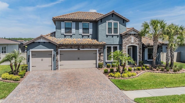 29043 Picana Ln, Wesley Chapel, FL 33543 - view of front of house with a tiled roof, stucco siding, stone siding, decorative driveway, and an attached garage