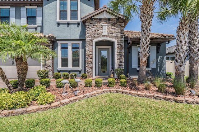 29043 Picana Ln, Wesley Chapel, FL 33543 - view of front facade with stucco siding, a front yard, stone siding, and a tile roof