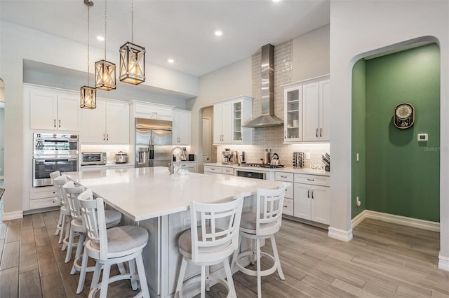 29043 Picana Ln, Wesley Chapel, FL 33543 - kitchen featuring wall chimney range hood, appliances with stainless steel finishes, a sink, a large island, and tasteful backsplash