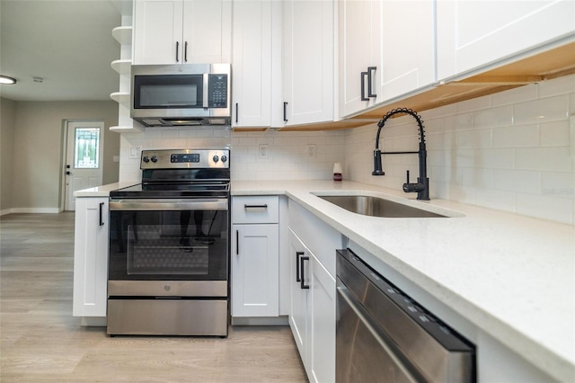 1403 Cummings Ave, Avon Park, FL 33825 - kitchen with stainless steel appliances, a sink, light wood-style flooring, backsplash, and white cabinetry