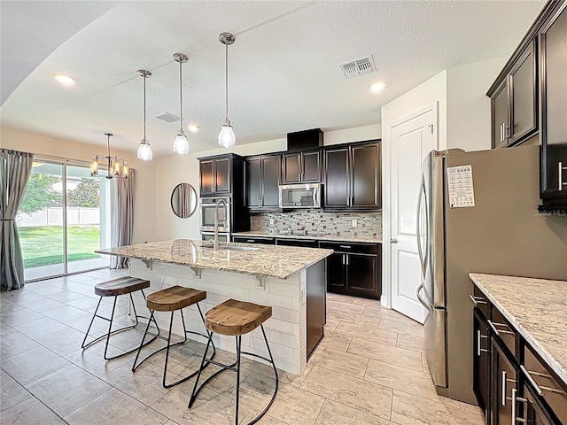 3184 Pinenut Dr, Apopka, FL 32712 - kitchen with stainless steel appliances, a kitchen bar, decorative backsplash, a center island with sink, and a sink