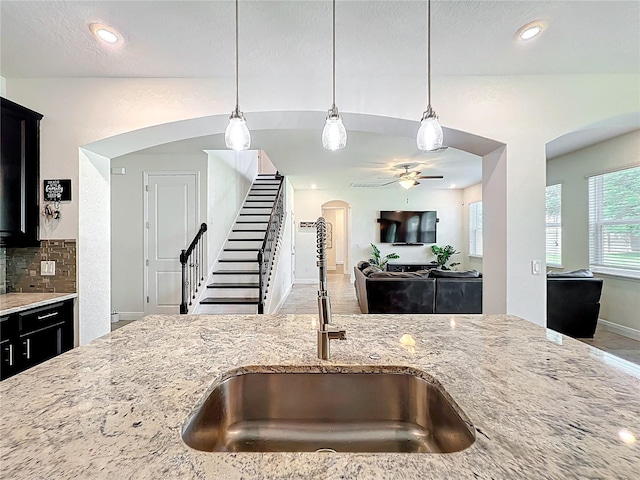 3184 Pinenut Dr, Apopka, FL 32712 - kitchen featuring a sink, light stone countertops, arched walkways, ceiling fan, and decorative light fixtures