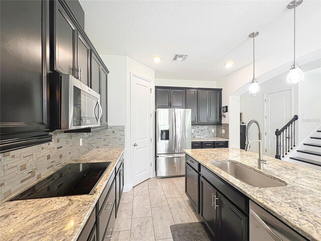 3184 Pinenut Dr, Apopka, FL 32712 - kitchen with stainless steel appliances, a sink, light stone counters, pendant lighting, and backsplash