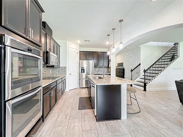 3184 Pinenut Dr, Apopka, FL 32712 - kitchen featuring appliances with stainless steel finishes, a sink, tasteful backsplash, light wood finished floors, and a textured ceiling