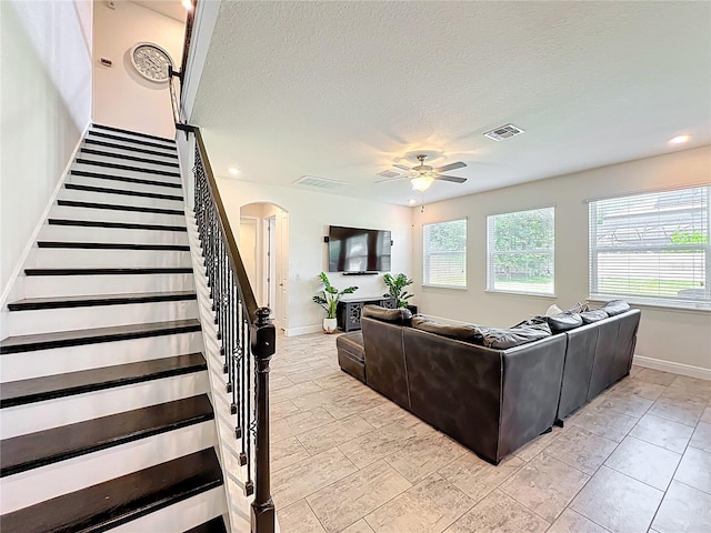 3184 Pinenut Dr, Apopka, FL 32712 - living area with arched walkways, ceiling fan, stairs, baseboards, and a textured ceiling