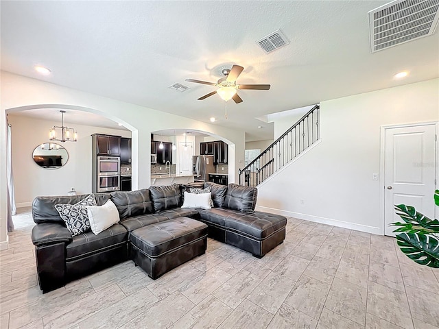 3184 Pinenut Dr, Apopka, FL 32712 - living room with arched walkways, ceiling fan, baseboards, a chandelier, and stairs